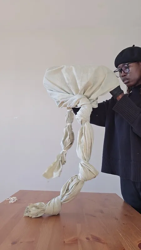 Diama holding sculpted fabric form on table