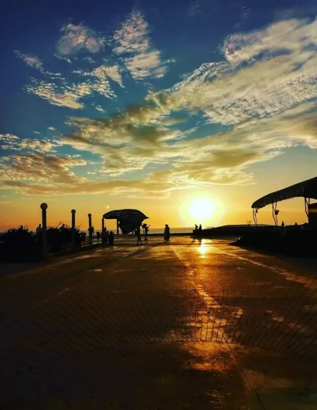 Boardwalk sunset with dramatic clouds and silhouettes