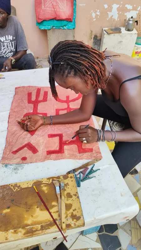 Diama painting bogolan symbols on fabric
