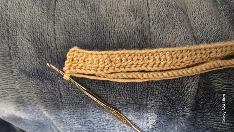 Gold crochet hook on grey fabric